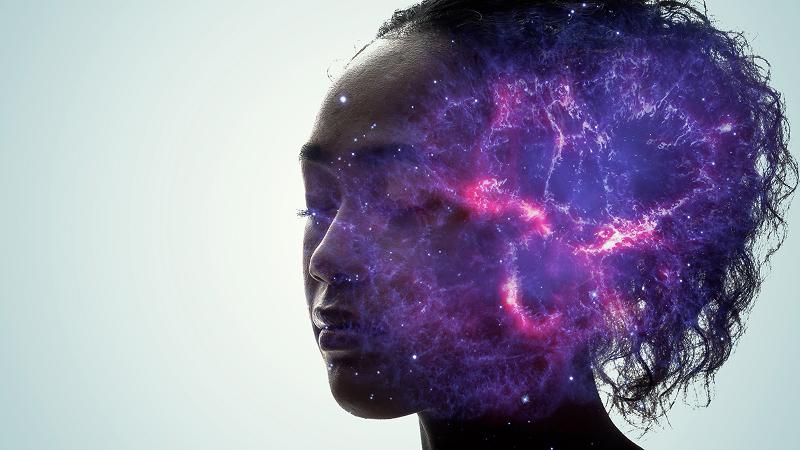 Profile of a person's head with purple and pink cosmic nebula imagery overlaid on the brain area against a light background.